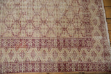 Distressed Oushak rug border featuring black cherry red starbursts and ivory trellis pattern, with visible wear.