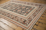 Distressed Oushak rug corner showing cherry red pawn and meandering vine border.