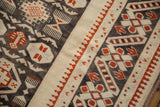 Distressed Oushak carpet's antique ivory border, cherry red pawn motif, and charcoal geometric patterns.