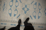 Distressed Oushak rug's ivory field, pale blue geometric motifs, even wear, and lazy line texture.