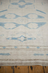 Distressed Oushak rug's pale blue geometric motifs and banded brown border on antique ivory.