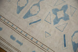 Distressed vintage Oushak rug with ivory pile, pale blue geometric relief, and chocolate brown border.