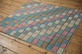 Angled close-up of distressed vintage Oushak rug's multi-color checkered pattern with abrashes and side selvage.