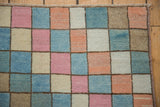Distressed Oushak rug with soft blush, sky blue, and beige checkered pattern showing abrashes.