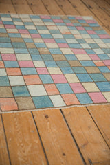 Visible pile texture and distressed pastel checkered motif on the vintage Oushak rug.