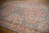 Distressed Oushak corner with scrolling floral border in terra cotta, blue, and ivory.