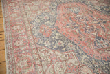 Worn terra cotta, dusty blue, and ivory vinery and border of vintage Oushak rug.