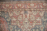 Distressed Oushak rug's floral vinery and low pile texture in terra cotta and denim blue.