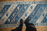 Distressed Oushak runner's blue diagonal stripes, delicate floral vinery, and starburst border.