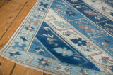 Corner of distressed Oushak runner, powder blue starburst pinwheel border, floral vinery motifs.