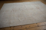 Corner detail of distressed vintage Oushak rug, showing faded ivory tones and subtle plant motifs.