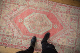 Distressed vintage Oushak rug close-up: faded cherry red stepped medallion and geometric pinwheel elements.