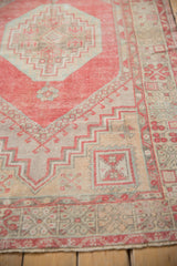 Distressed Oushak rug corner showing pinwheel elements and geometric borders in cherry red, beige, and blue.