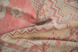 Worn texture and clear zigzag geometric patterns on a folded vintage Oushak rug.