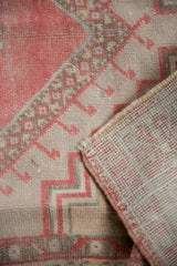 Distressed Oushak rug's folded corner with intact selvages, hand-knotted reverse, and worn red, beige pile.