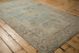 Angled view of a distressed Oushak rug showing its soft worn texture and pale blue medallion.