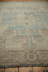 Angled view of a vintage Oushak rug showing the soft, evenly worn pile and charcoal-outlined geometric motifs.