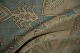 A soft fold in the distressed Oushak rug reveals the even texture and low, hand-knotted pile.
