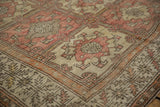 Distressed Oushak carpet corner with serrated leaf border and blush, beige floral panels.