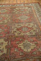 Vintage distressed Oushak rug showing blush and beige geometric floral motifs with textural wear.