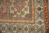 Vintage distressed Oushak rug displaying tangerine orange border with serrated leaf motifs.