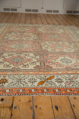 Vintage Oushak rug detail: blush and ivory panels, tangerine border, serrated leaves pattern.