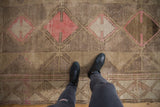 Vintage distressed Oushak carpet with geometric paneled medallions and subtle abrashes in pink, ivory, and beige.