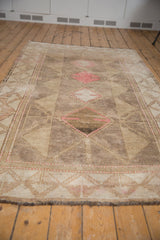 Distressed Oushak rug with geometric paneled medallions, wide border, in muted beige and pink.