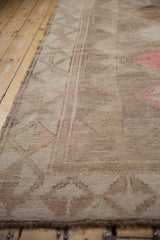 Distressed Oushak rug texture, showing faded geometric patterns and intact side selvage.