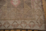 Distressed Oushak rug corner, showing wide tone-on-tone border and faded pink motifs.