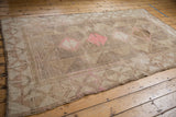 Intact side selvage and wide geometric border of the distressed Oushak rug in beige, pink.