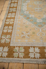 Wide bronze border with pale quatrefoil florals on distressed vintage Oushak rug corner.