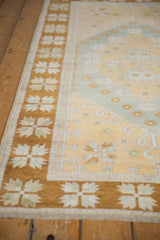 Distressed wide bronze border featuring ivory quatrefoil flowers on a vintage Oushak.