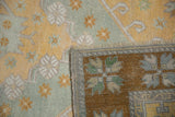 Distressed Oushak rug corner folded, revealing saffron pile, dusty blue, selvage, and woven bronze back.