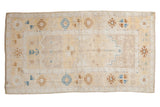 Distressed vintage Oushak runner with muted ivory, pale saffron, and sapphire blue motifs.