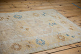 Distressed pale saffron Oushak runner showing blue germinating plant and bird motifs.