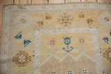 Vintage Distressed Oushak rug section with pale saffron field and sapphire blue plant motifs.