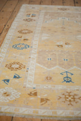 Distressed Oushak runner with pale saffron field and blue bird motifs.