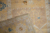 Folded corner of vintage distressed Oushak rug showing soft pile and faded saffron geometric border.
