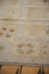 Vintage distressed Oushak rug with soft, time-worn ivory pile, faded floral patterns, and neat fringe.