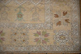 Distressed vintage Oushak rug corner: pale saffron field, geometric border, plant, floral motifs.