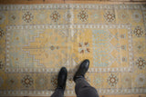 Distressed Turkish Oushak rug in pale saffron yellow with geometric and stylized floral motifs.