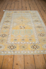 Textured distressed Oushak rug with pale saffron yellow field and geometric patterned border.