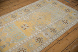 Distressed Oushak rug detail with pale saffron yellow, germinating plant motifs, and wide floral-geometric border.