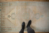 Distressed Oushak rug's upper corner, revealing stepped geometric motifs and worn texture.