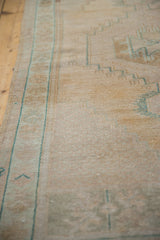 Distressed vintage Oushak rug showing faded dusty teal geometric border and soft pile.