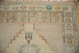 Distressed Oushak rug corner with abrashed silver field and dusty teal geometric borders.