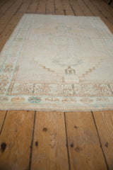 Distressed Oushak rug border and soft fringe, displaying pale saffron and dusty blue geometrics.