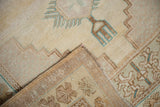 Distressed vintage Oushak rug corner reveals textured pile, reverse, dusty teal, and intact selvage.