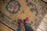 Distressed vintage Oushak rug with faded Rococo rose medallion and wide field abrashes.